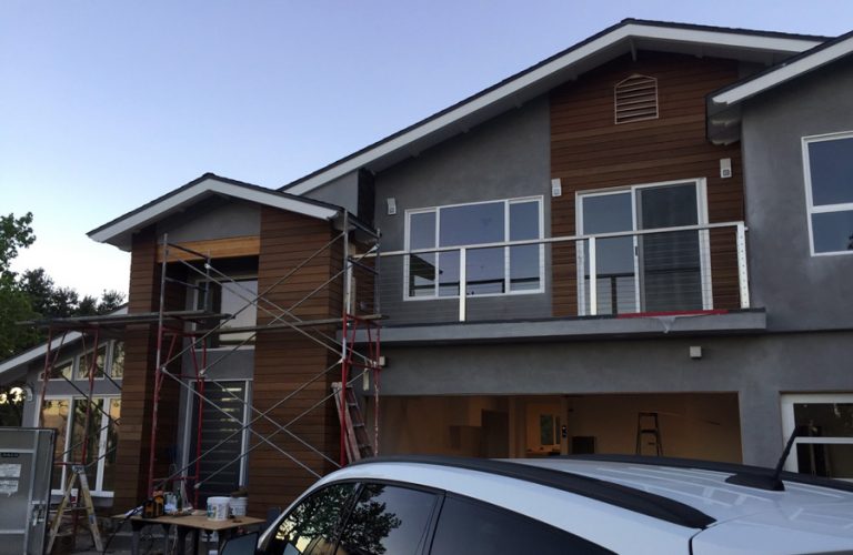Two-story exterior during construction with scaffolding and wood accents.