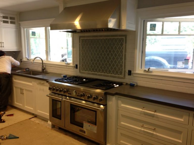 Large gas range and double oven beneath a stainless steel hood.