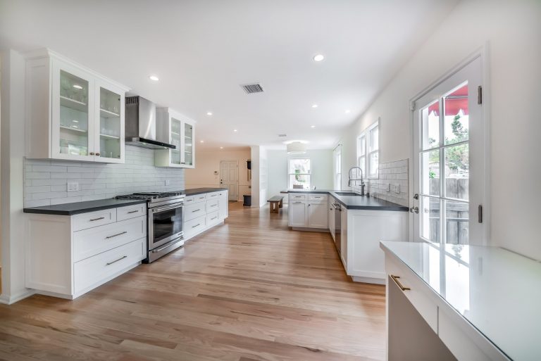 Long view through kitchen with range at left and sink at right.