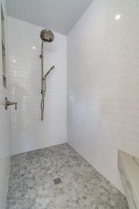 Walk in shower with subway tile and marble bench