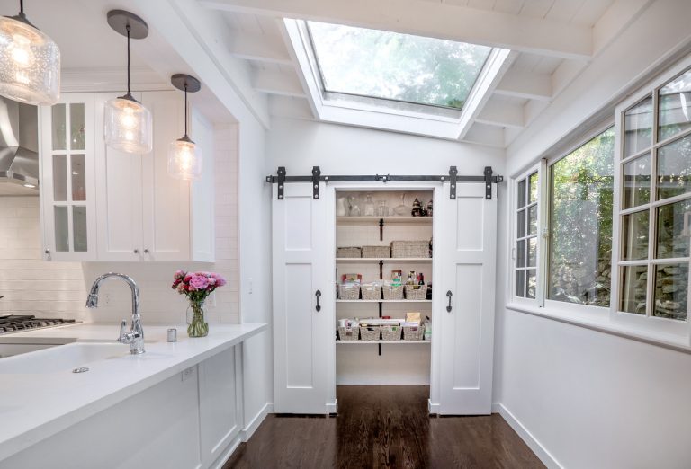 White kitchen with a skylight and an open pantry behind sliding doors.