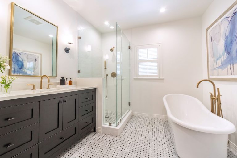 Bathroom overview with dark double vanity, glass shower and freestanding tub.