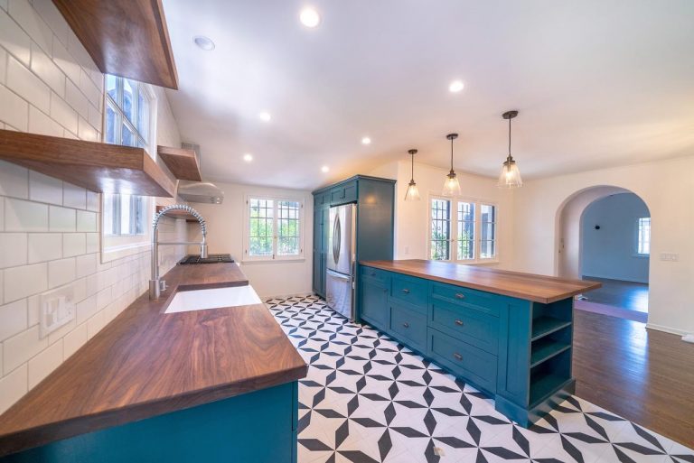 Blue kitchen island and wood counters above black-and-white geometric floor tile.