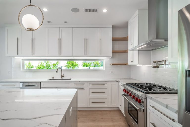 White kitchen sink wall and range with light counters.