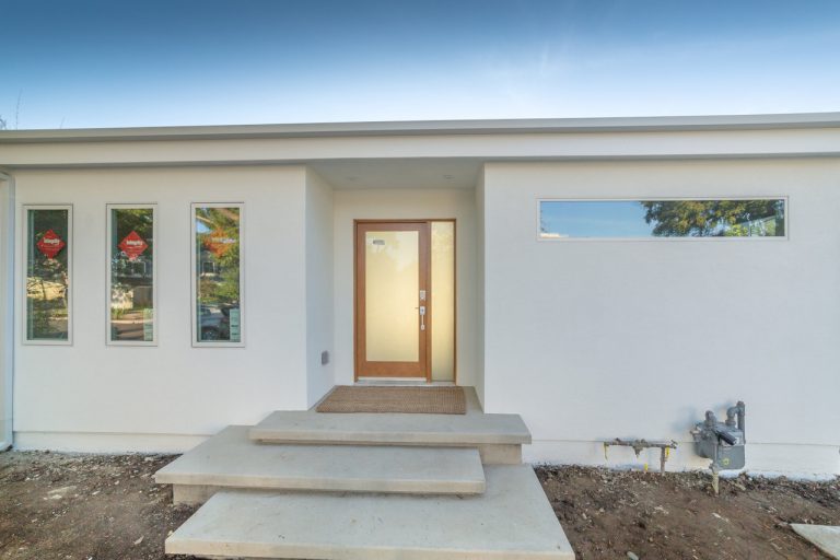 White home exterior with a wood-framed front door and entry steps.