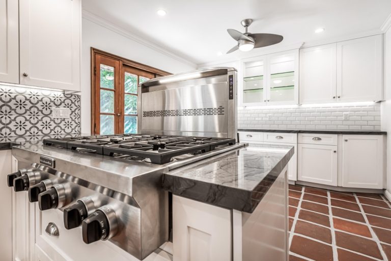 Gas cooktop and veined countertop beside white drawers.