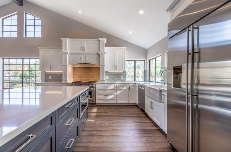 White kitchen cabinets and dark island beneath a sloped ceiling.