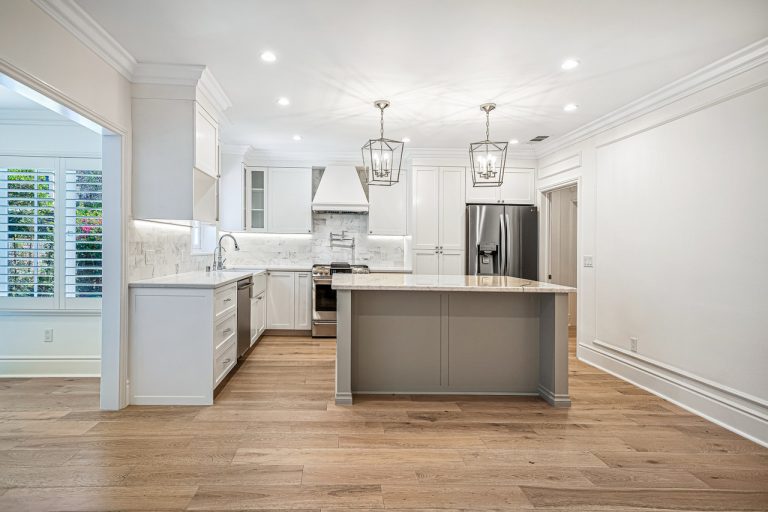 Open kitchen with white cabinetry, a gray island and pendant lights.