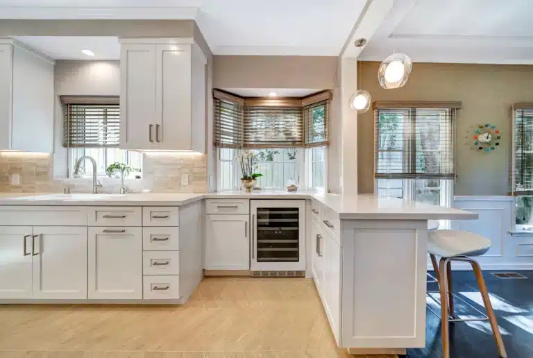 Kitchen sink wall and beverage refrigerator beside a breakfast counter.