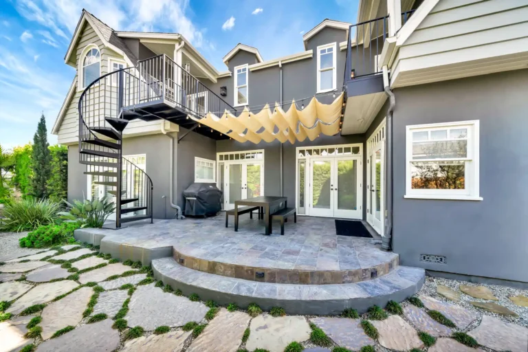 Rear patio with a pergola, outdoor table and spiral staircase.
