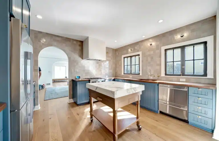 Wide kitchen view with wood counters and a pale tiled wall.