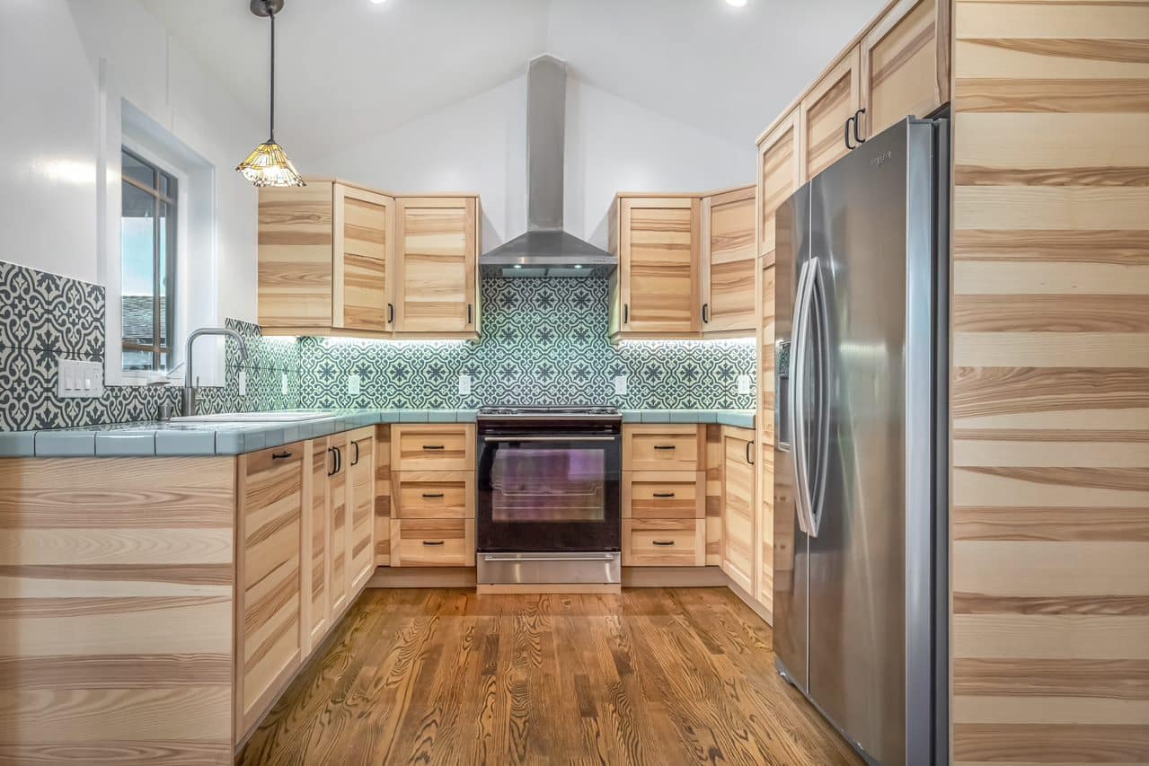 Kitchen aisle with sink, gas range and wood cabinetry.
