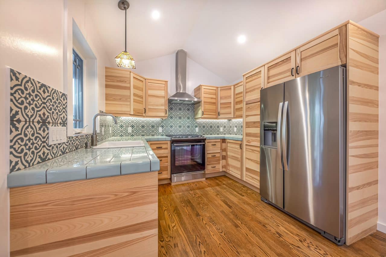 Wood kitchen cabinets and stainless steel refrigerator beside the peninsula.