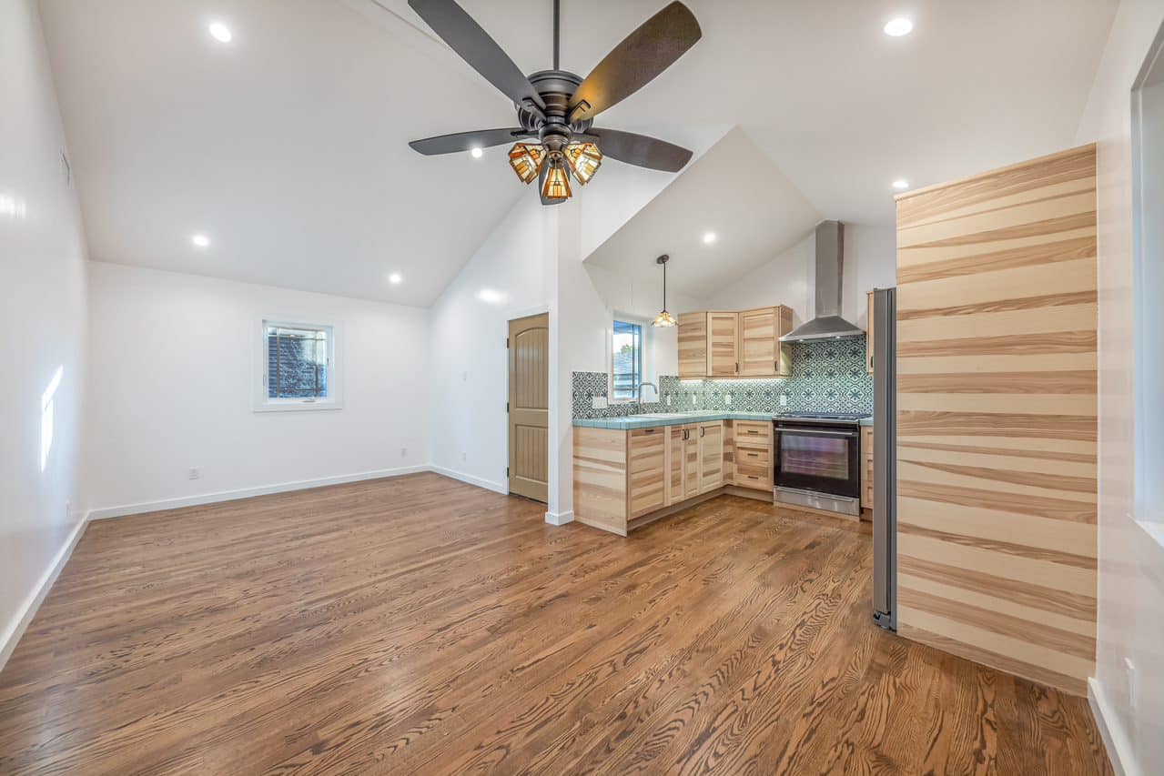 Open living area with ceiling fan and wood kitchen cabinetry.