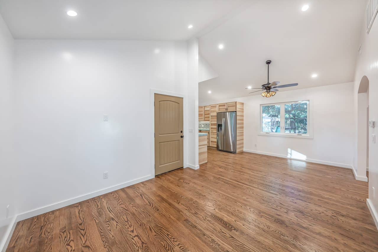 Long living area with wood flooring and kitchen at the far end.