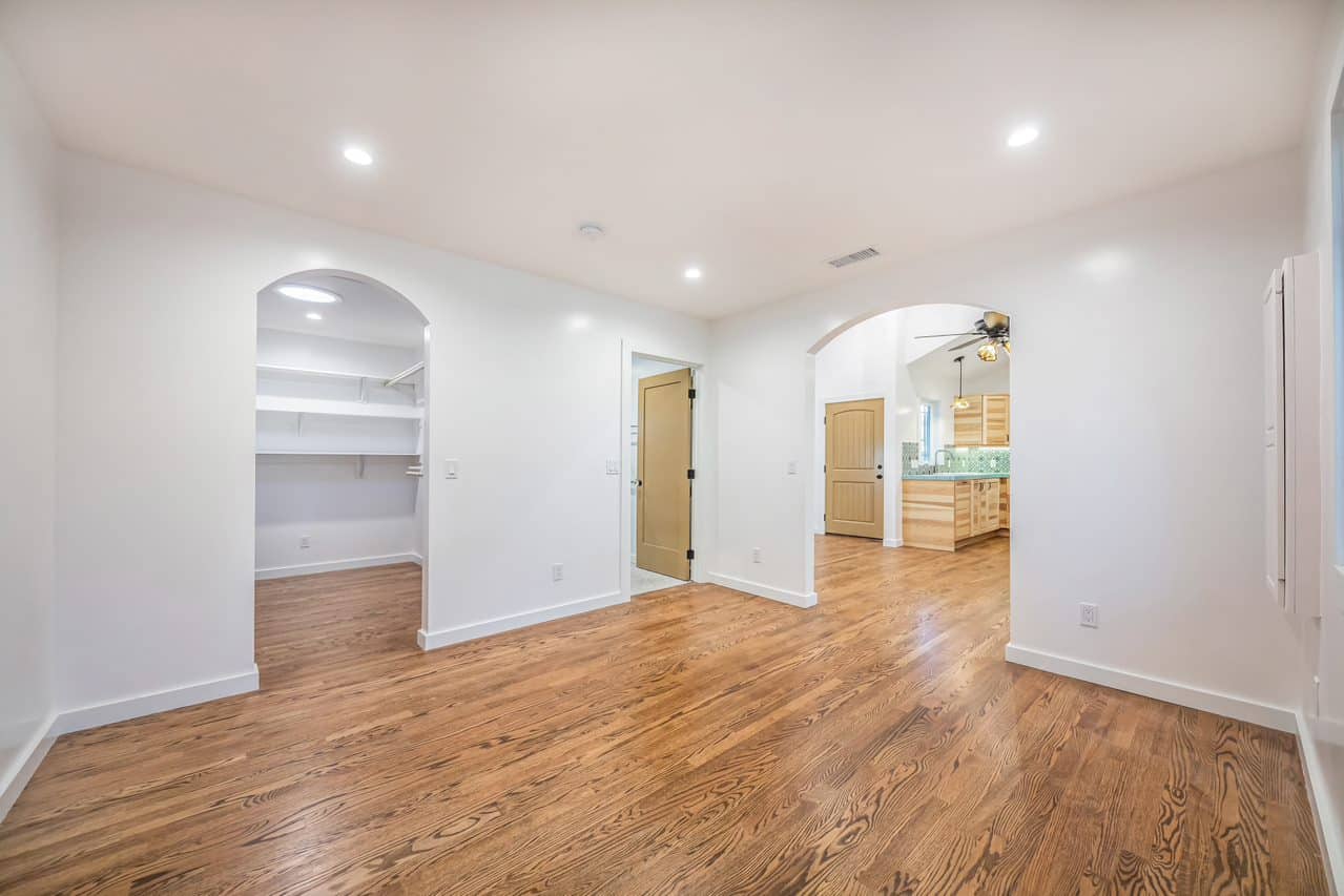 White room with an open closet and arched kitchen doorway.