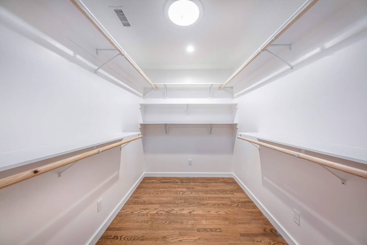 Walk-in closet with shelving, hanging rails and wood flooring.