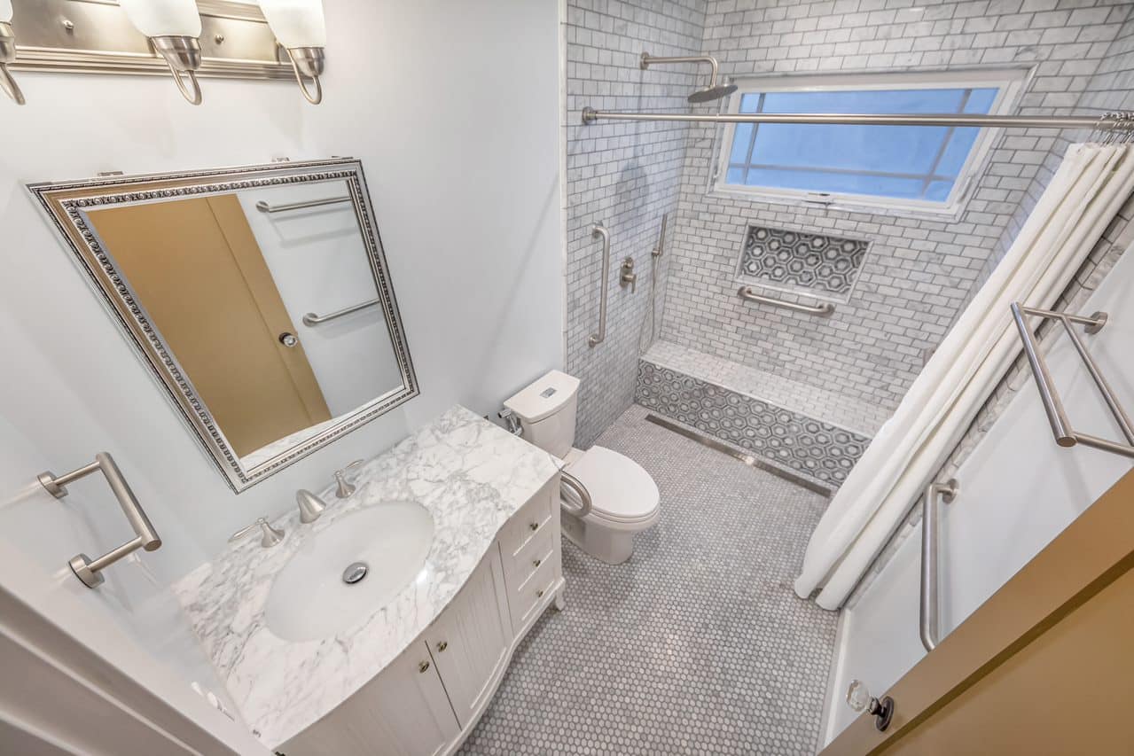 Overhead bathroom view with white vanity, toilet and tiled shower.